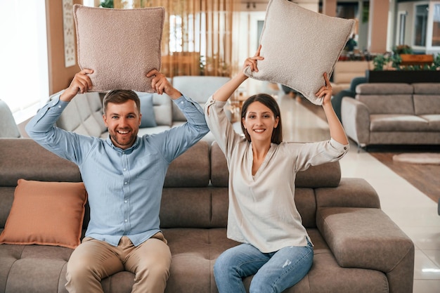 Plezier maken met kussens Echtpaar kiest de bank en het bed in de winkel