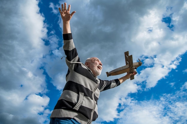 Plezier senior gepensioneerde man volwassen man bij pensionering oude man op hemelachtergrond met speelgoed vliegtuig buiten