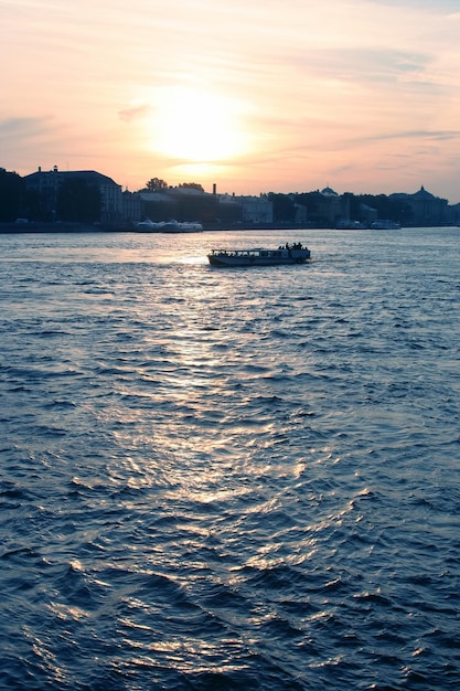 Plezierboot drijft op de rivier bij zonsondergang