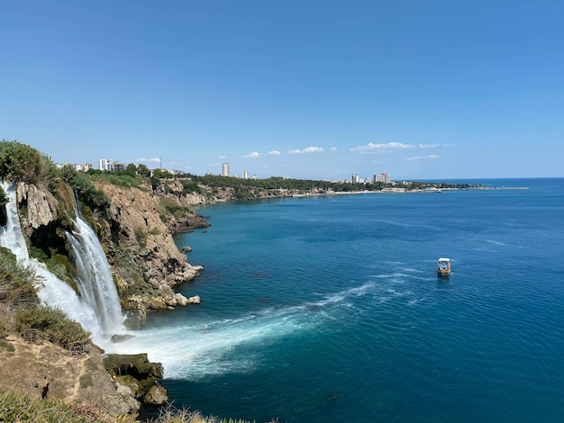 Pleziervaartuigen in de zee bij de kust met een waterval