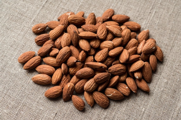 A plie of loose almonds on the canvas background