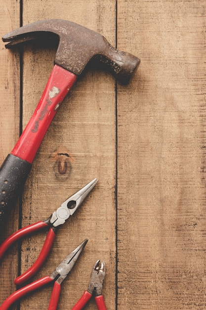 Pliers and hammer on wooden table.