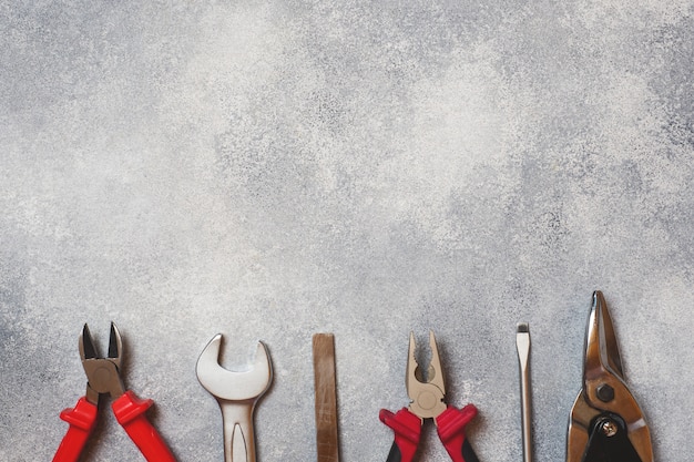 Pliers, screwdrivers and wrench combination on grey concrete background with copy space. 