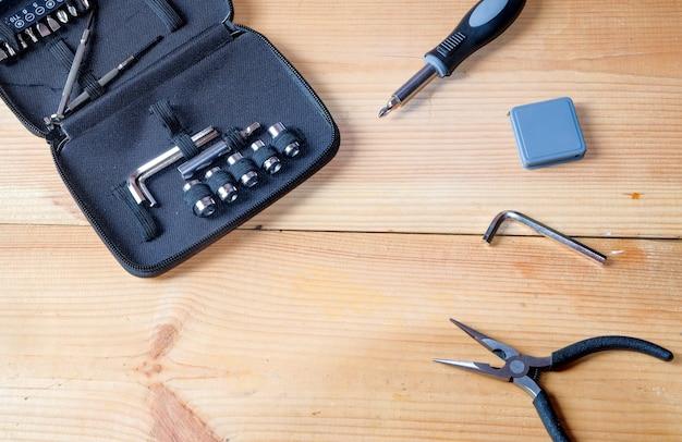 Pliers, screwdrivers, wrenches, meters and other a portable tools kit for technician put on wooden plate .