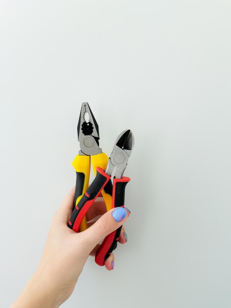 pliers wire cutters of bright colors on isolated white background in female hands female manicure