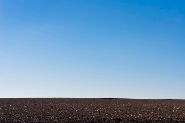 Ploughed field and blue sky as a background