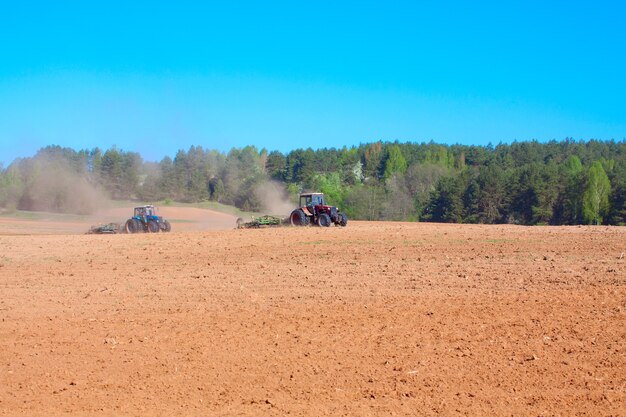 Ploughing tractor during cultivation agriculture works at field with plough