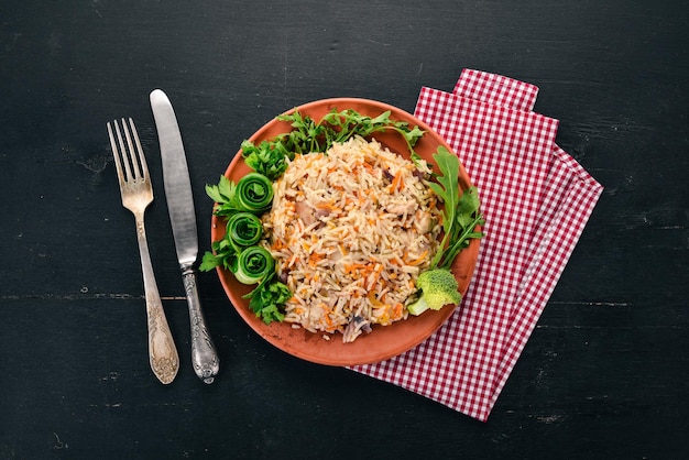 접시에 고기와 야채를 곁들인 플로브 라이스 우즈베키스탄 요리 나무 배경 위에 있는 평면도 복사 공간