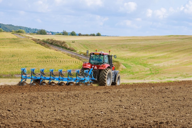 Фото Вспашка поля большой плуг на тракторе трактор с сельскохозяйственным навесным оборудованием