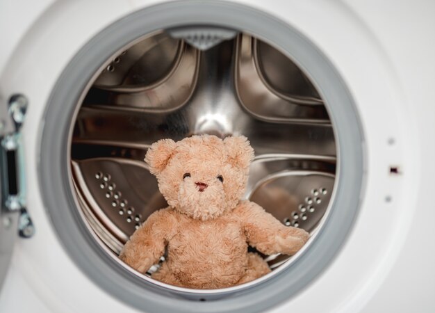 Pluche teddybeer na het wassen in de machine die binnen zit met open deur