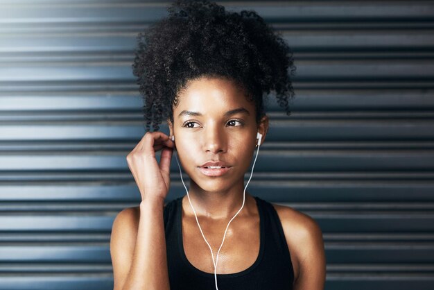 Plug in and get moving Shot of a sporty young woman listening to music while exercising against a grey background