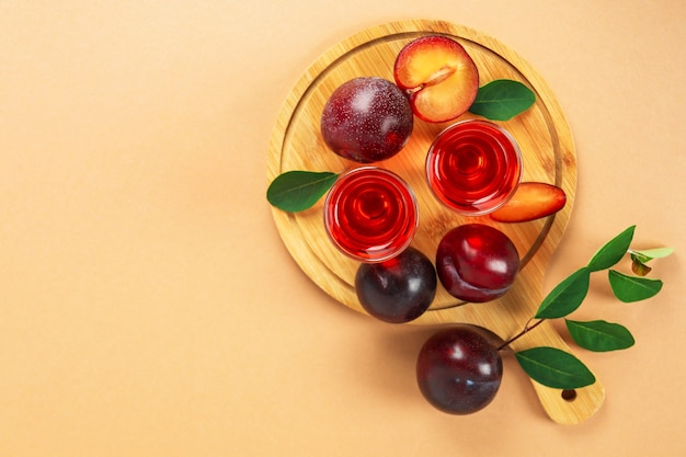 Plum brandy shots and ingredients on beige background