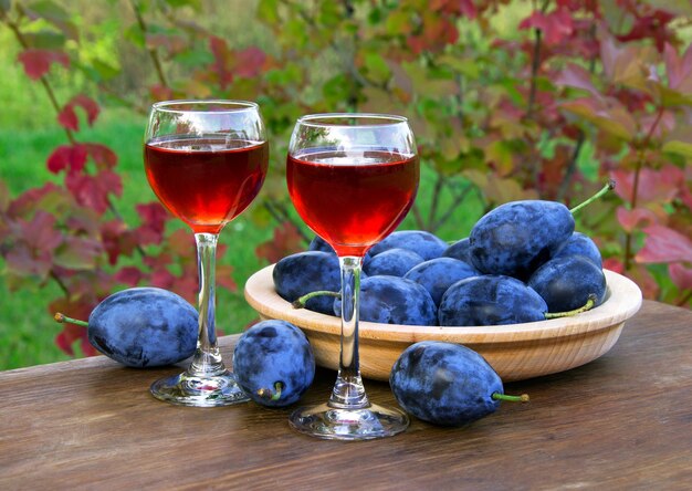 Plum drink in a glass wineglass with plums on a natural background
