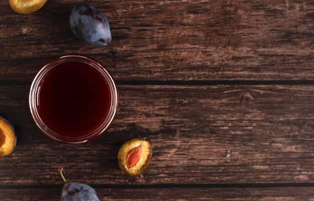 Plum jam in a glass jar on a wooden background with copy space