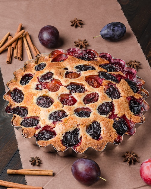 Plum pie on a dark wooden background. Homemade baking