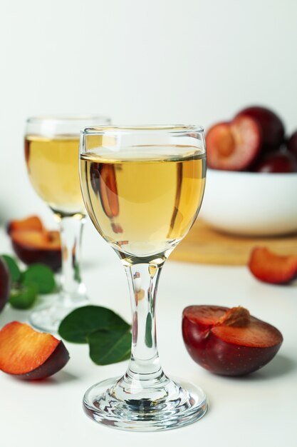 Plum vodka shots and ingredients on white background