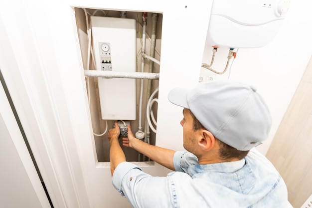 Plumber Adjusting Temperature Of Electric Boiler.