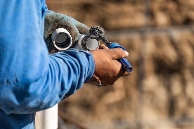 Plumber Applying Pipe Cleaner Primer and Glue to PVC Pipe At Construction Site