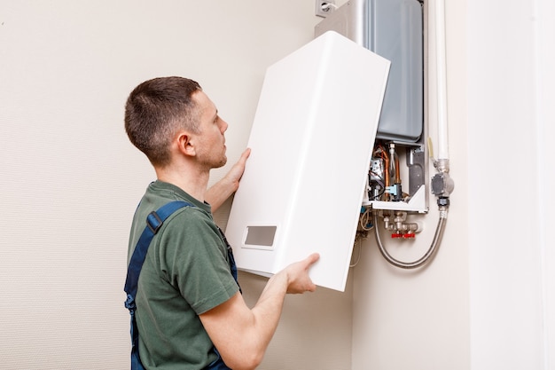 Photo plumber attaches trying to fix the problem with the residential heating equipment. repair of a gas boiler