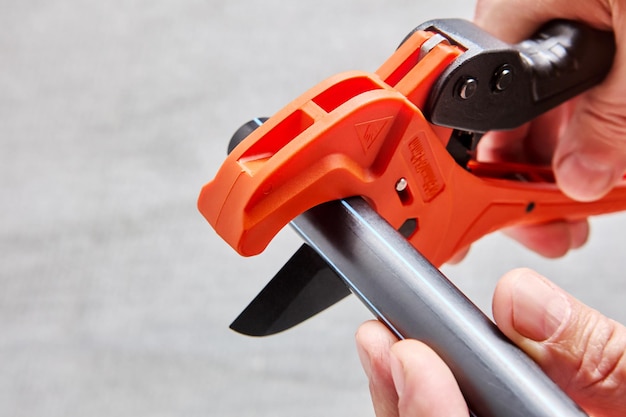 Photo plumber cuts end of plastic pipe with cutter