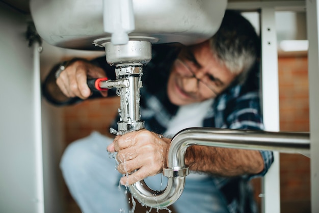 Photo plumber fixing the kitchen sink