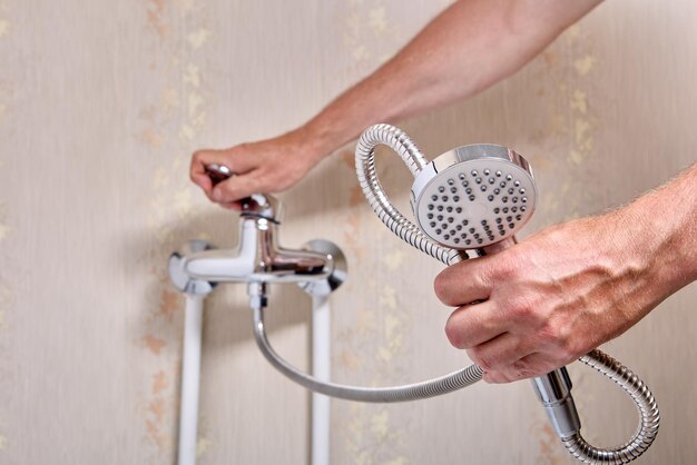 Plumber fixing leaky single handle shower faucet in bathroom