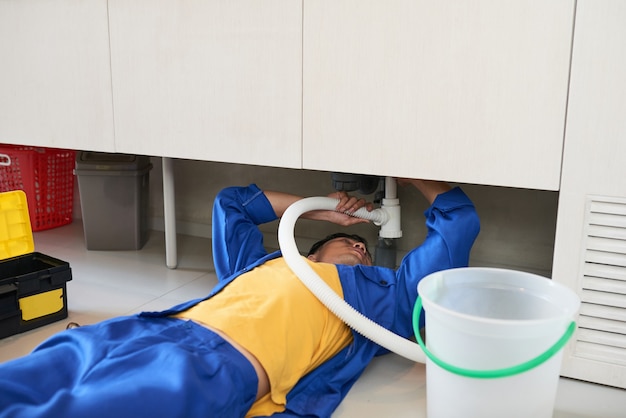 Photo plumber fixing sink pipe