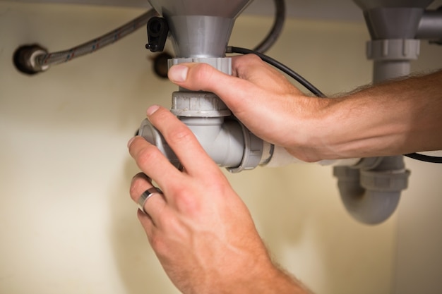 Plumber fixing under the sink