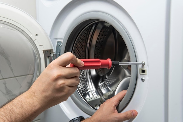 Plumber fixing washing machine in bathroom closeup