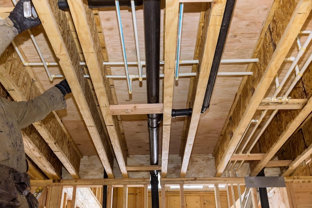 Plumber gluing sewage drain pvc pipes on the home under construction the wastewater system