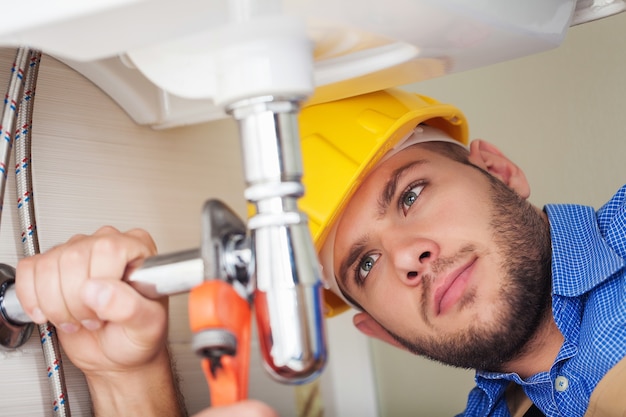 Plumber hands fixing water tap on background