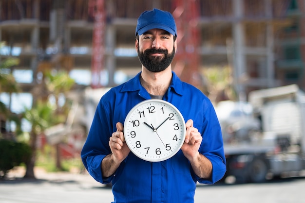 Photo plumber holding clock on unfocused background