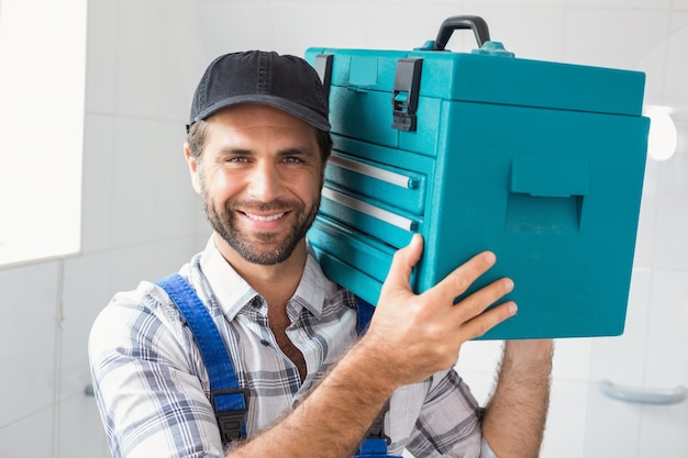 Photo plumber holding toolbox on shoulder