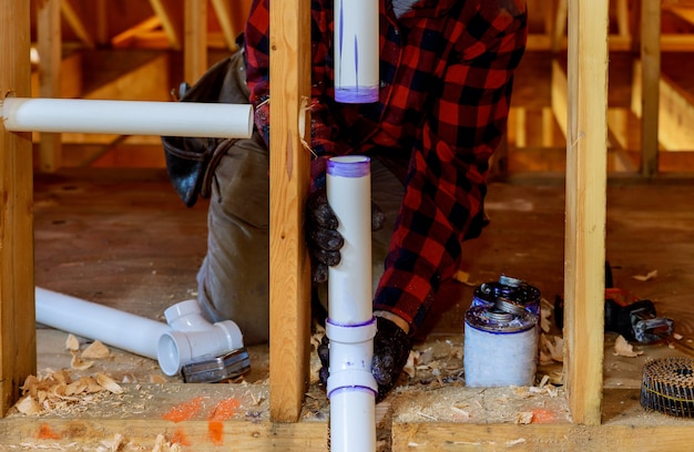 Сантехник устанавливает грунтовку и клей ПВХ трубы на строительстве дома