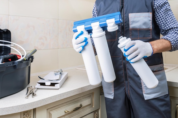 Plumber man installs or change water filter in the kitchen