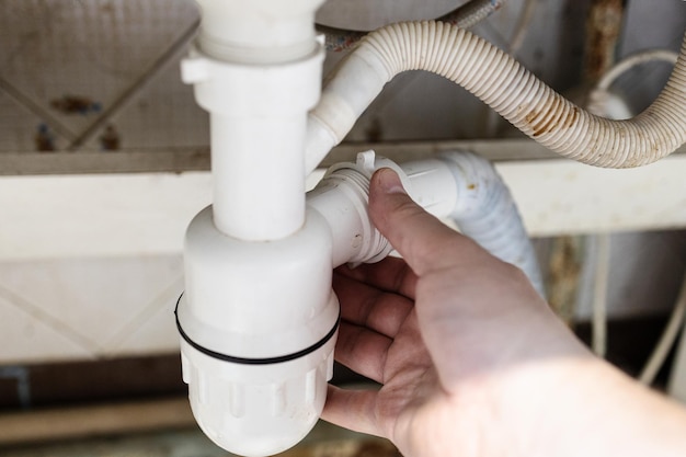 Plumber mounts plastic siphon closeup in kitchen