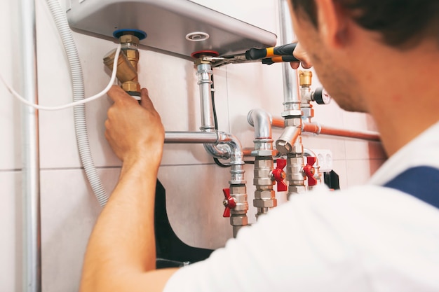 Plumber screwing nut of pipe in the heating system in the boiler room