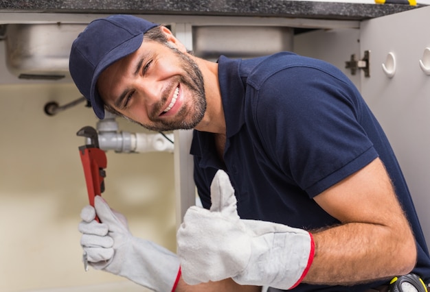 Photo plumber smiling at the camera fixing under the sink