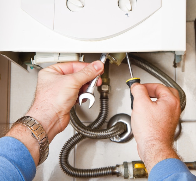 Plumber at work. Servicing gas boiler