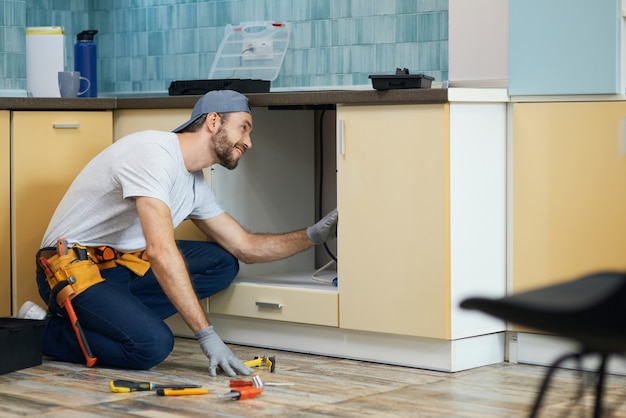 The plumber you can count on full length shot of cheerful young plumber wearing tool belt smiling