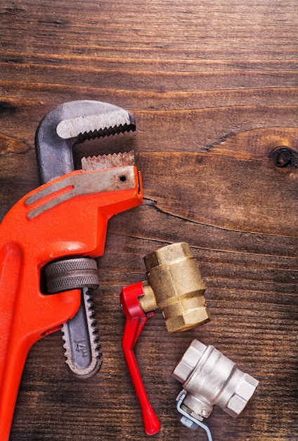 Plumbers fixtures and monkey wrench on vintage wooden board