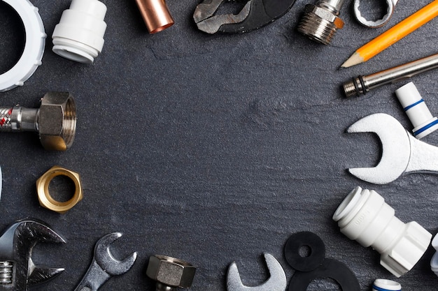 Plumbing concept tools and pipes on a dark slate bakground