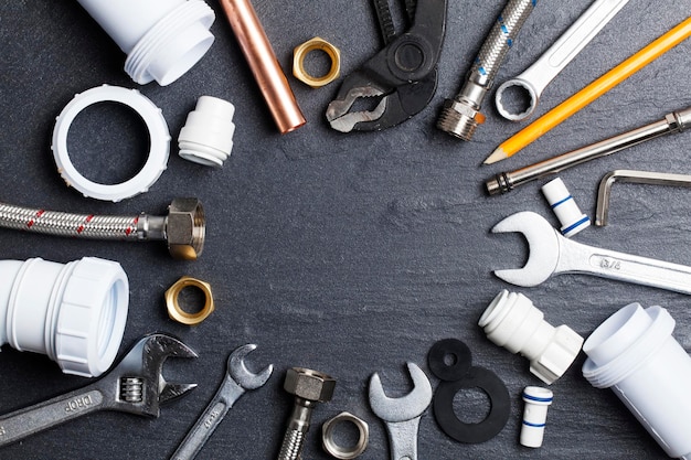 Plumbing concept tools and pipes on a dark slate bakground