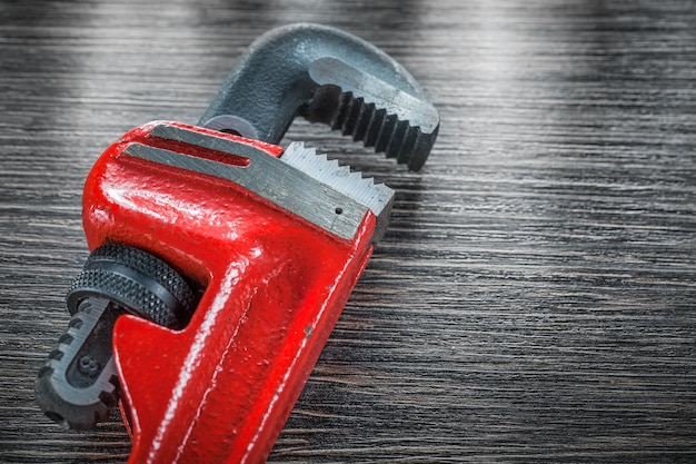 Plumbing pipe wrench on vintage wooden board.