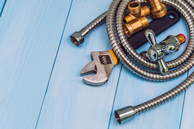 Plumbing tool, faucet and hose on blue wooden boards are used to replace or repair