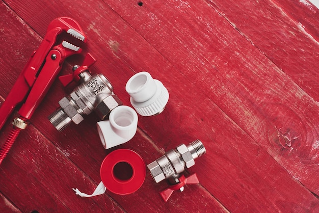 Plumbing tools and equipment on a red wooden background close\
up