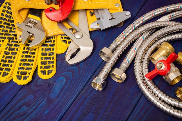 Plumbing tools in the yellow bag and spare parts on blue wooden boards are used to replace or repair