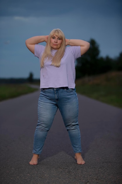 Полная женщина средних лет позирует в джинсах на улице с лишним весом xxl Полная девушка наслаждается жизнью