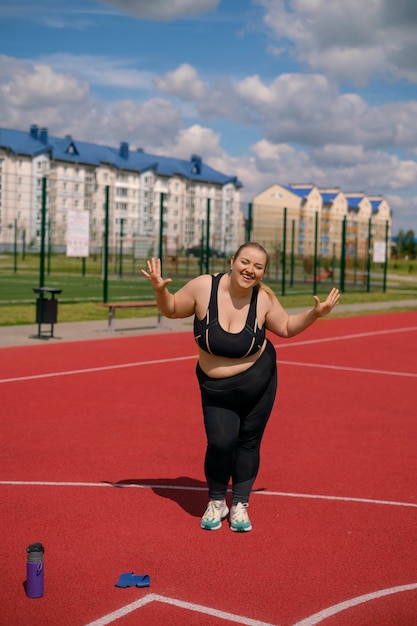 Plump woman in sports clothes stands laughing merrily