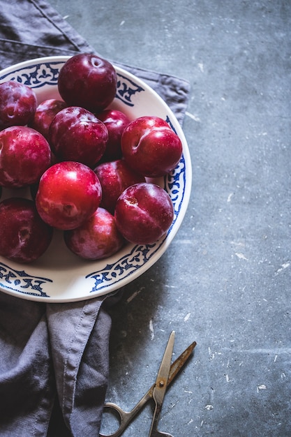 Plums of different varieties in a white ceramic plate with a pattern